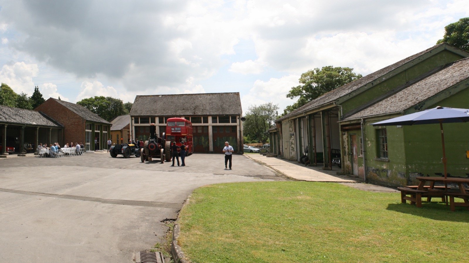 Historic military hangars and technical buildings at Bicester Heritage with vintage vehicles and visitor seating on the central lawn, photographed in June 2014.