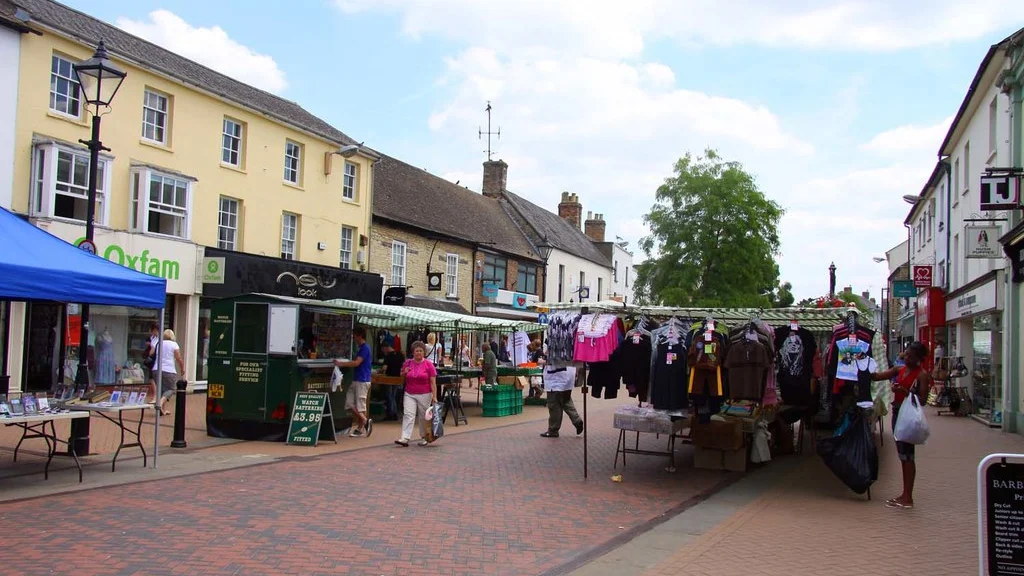 Street market stalls and shoppers on a pedestrianised street in Bicester town centre, photographed in June 2010.