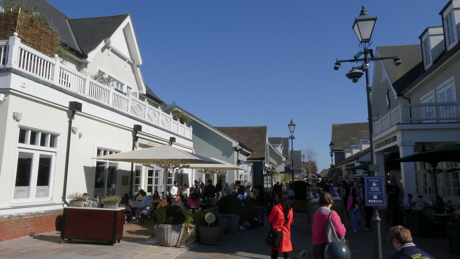 Pedestrians along the open-air designer shopping boulevard and cafe terraces at Bicester Village.