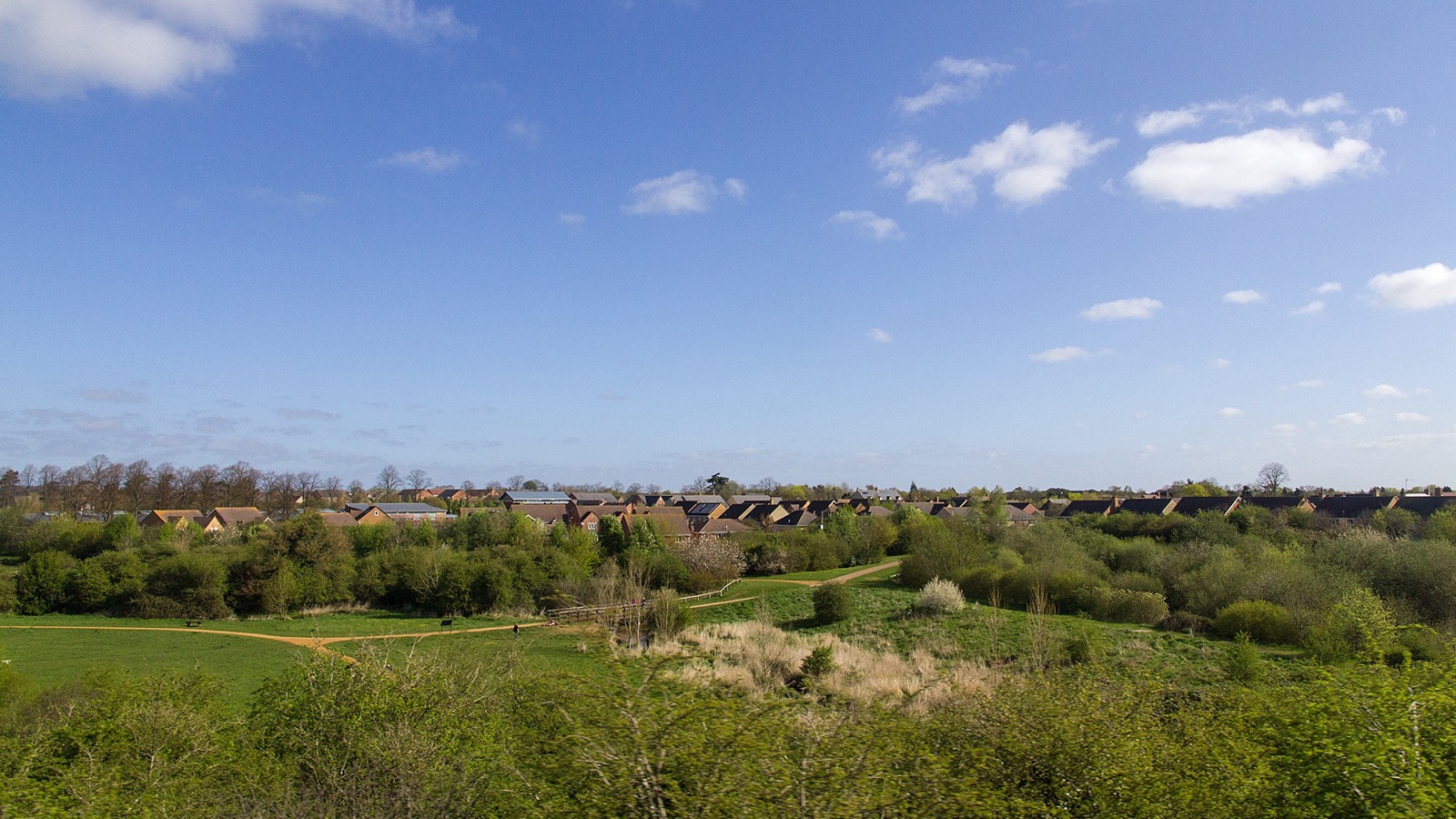 Sunny panoramic landscape view across the meadows, paths, and trees of Bure Park Nature Reserve, photographed in April 2014.