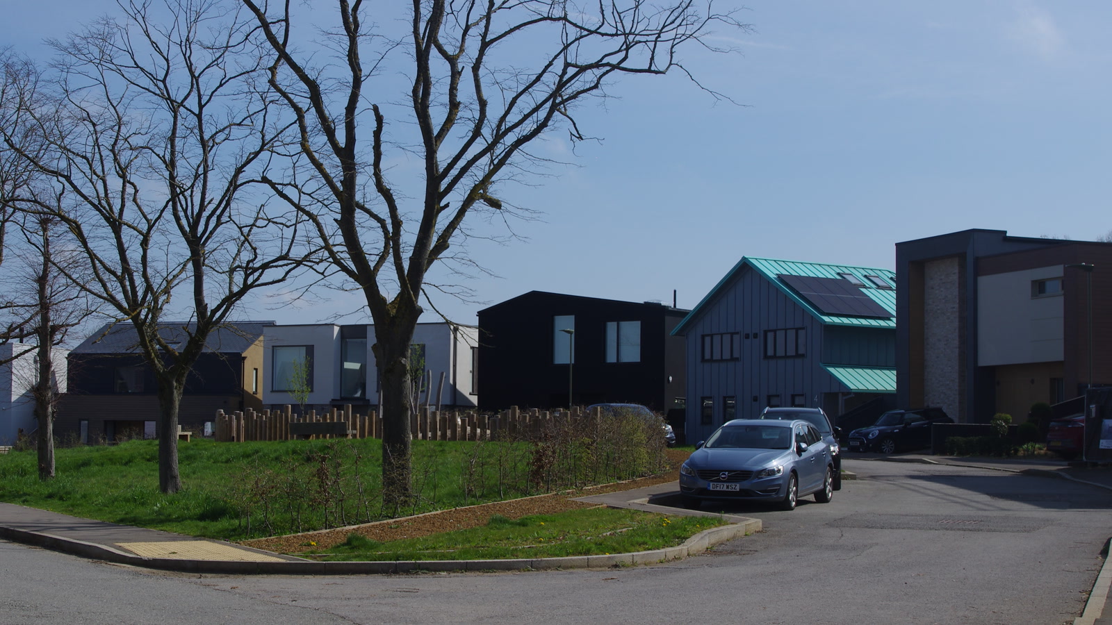Bespoke modern self-build homes featuring distinct architectural designs, green metal roofing, and timber cladding at Graven Hill, photographed in April 2023.