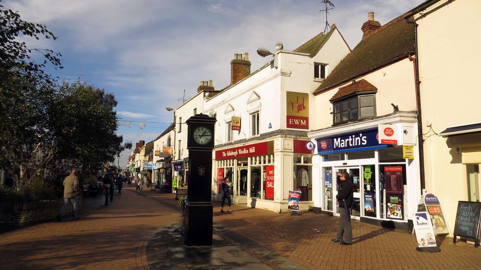 Pedestrianised retail street in Bicester town centre showing shopfronts and shoppers on Sheep Street.