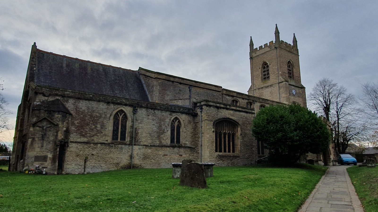 St Edburg's Church in Bicester showing its medieval stone tower, Gothic windows, and churchyard lawn, photographed in November 2022.